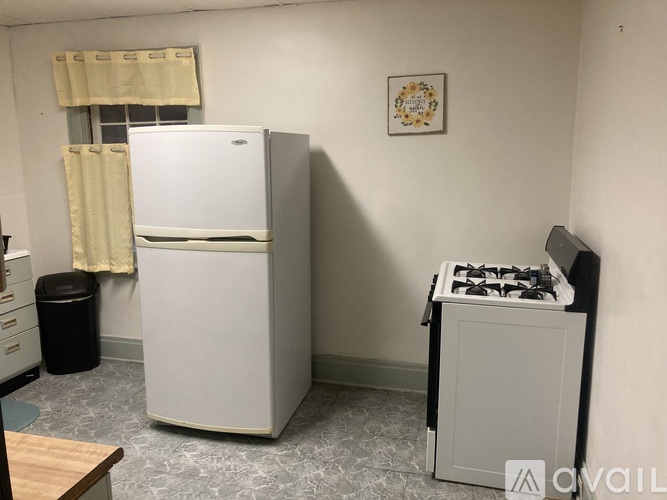 A small kitchen with a white fridge, a black trash can, and a small white stove.