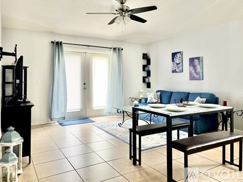 A living room with a blue couch and a white dining table.