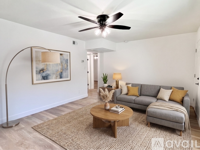 A living room with a grey couch, a coffee table, a floor lamp, and a painting on the wall.