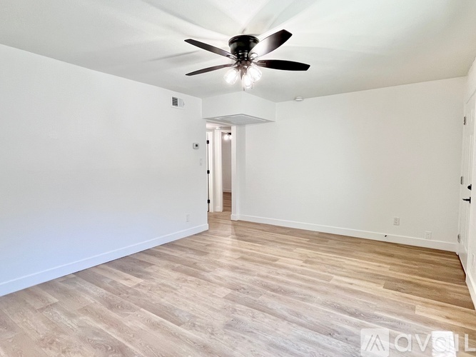 A spacious room with a ceiling fan and light fixture.