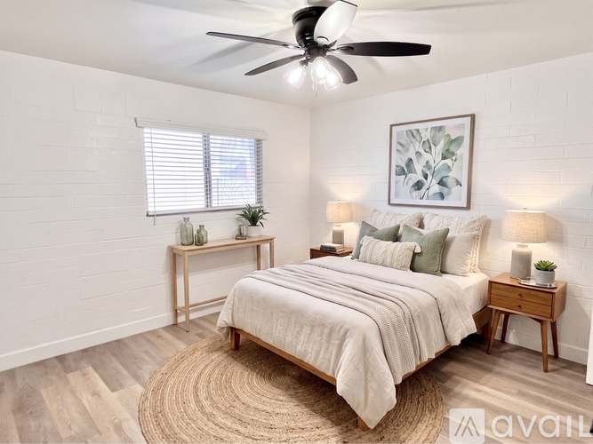 A bedroom with a large bed, a ceiling fan, and a rug on the floor.