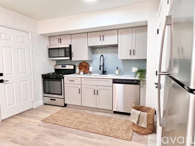 A kitchen with white cabinets and a wooden floor.