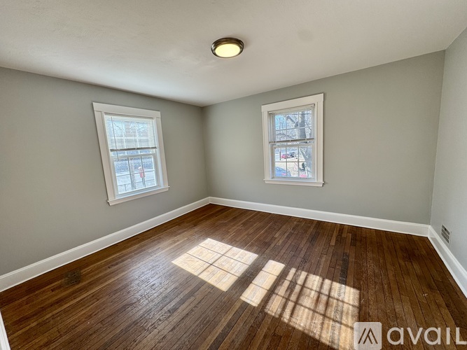 A room with wooden floors and two windows.