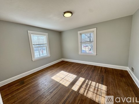 A room with wooden floors and two windows.