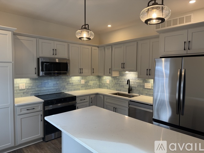 A kitchen with a white counter top and stainless steel appliances.