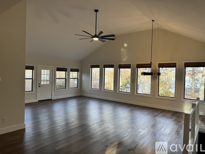 A spacious room with a ceiling fan and large windows.