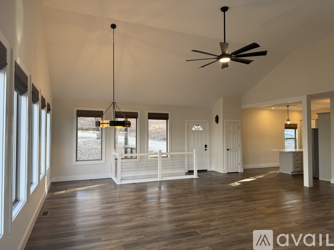 A spacious room with a ceiling fan and pendant lights.