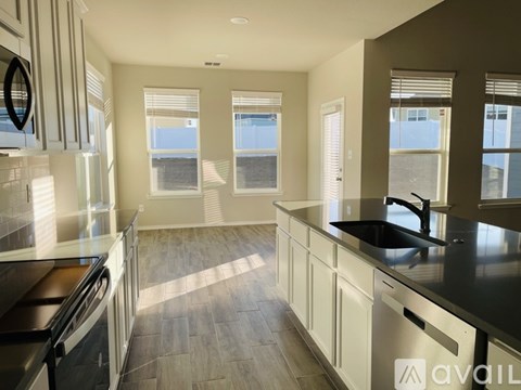 A kitchen with a black counter top and white cabinets.