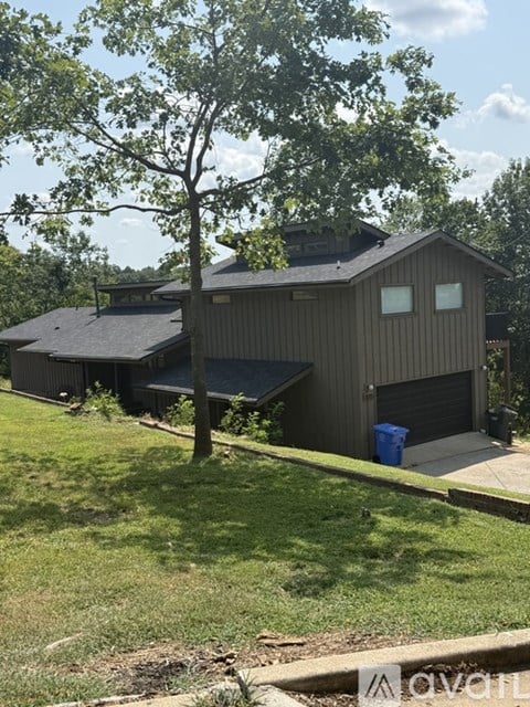 A house with a grey roof and a tree in front of it.