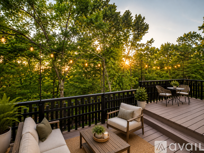 A wooden deck with a table and chairs overlooking a forest at sunset.