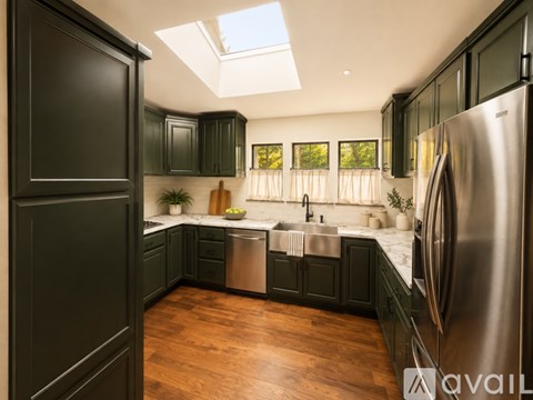 A kitchen with black cabinets and a stainless steel refrigerator.