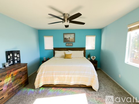 A bedroom with a bed, dresser, and ceiling fan.