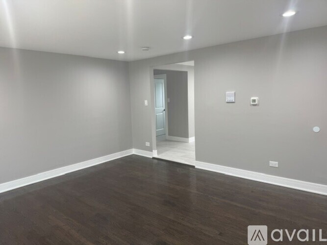 A spacious room with wooden flooring and a doorway leading to another room.