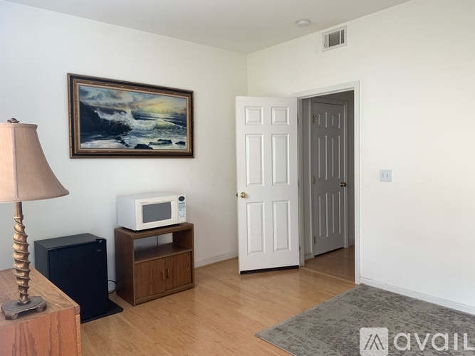 A room with a painting, a lamp, a microwave, and a door.
