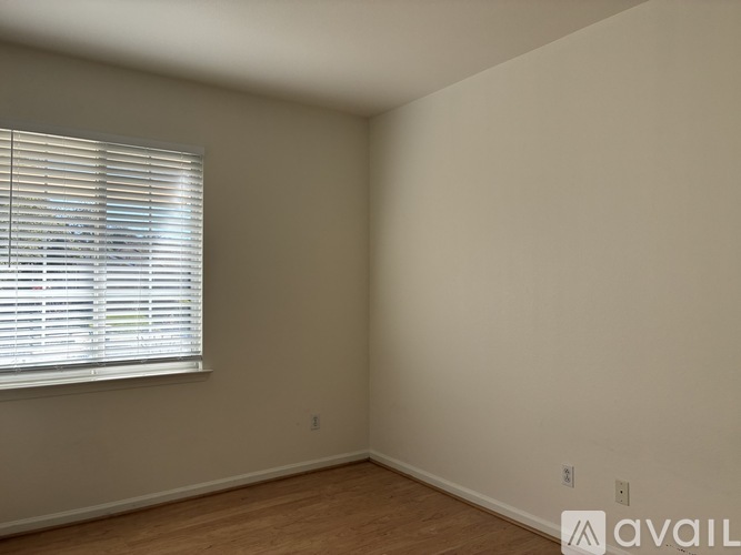A room with a window covered in blinds and wooden flooring.