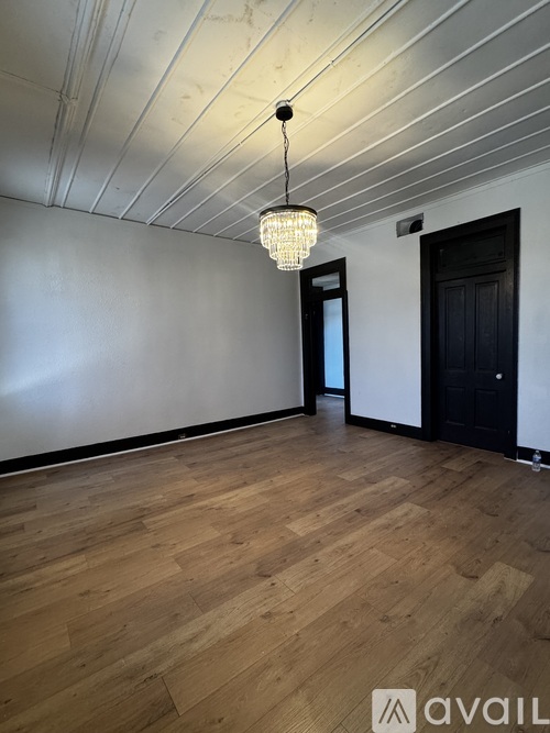 A room with wooden floors and a chandelier hanging from the ceiling.