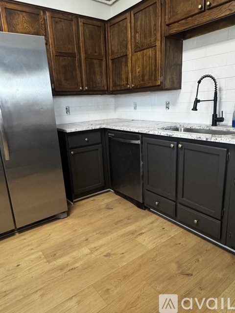 A kitchen with wooden cabinets and a stainless steel refrigerator.