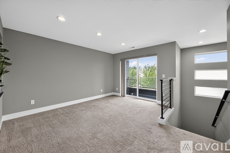 A spacious room with a carpeted floor and a view of trees through the glass door.