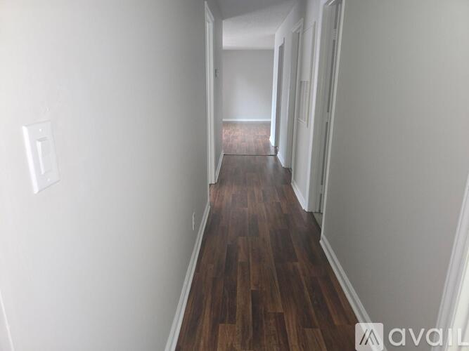 A long hallway with wood floors and white walls.