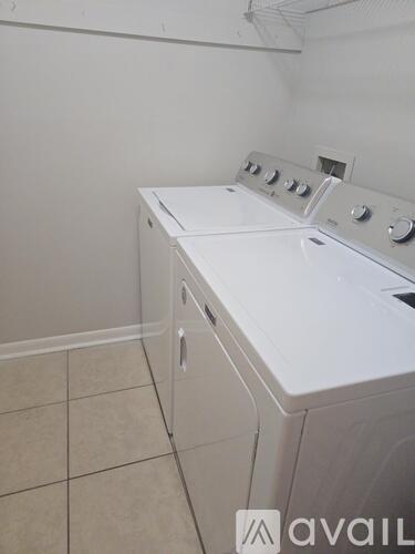 A white washing machine in a room with tiled flooring.