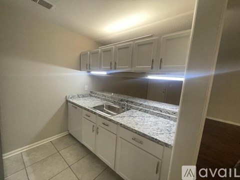 A kitchen with white cabinets and a granite countertop.