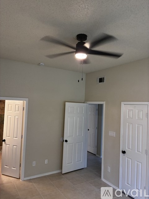 A room with a ceiling fan and three doors.