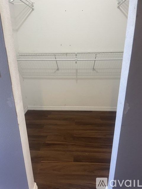 Empty room with a white wall and a wooden floor.