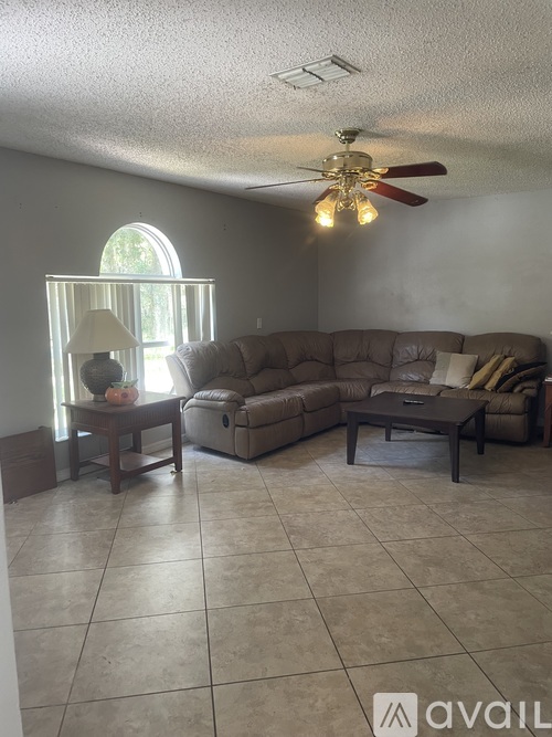 A living room with a couch, a coffee table, and a fan.