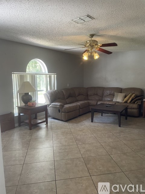 A living room with a couch, a coffee table, and a fan.