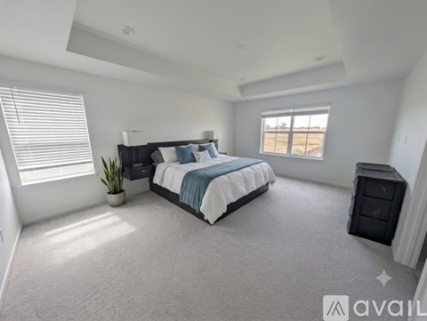 A bedroom with a large bed and a window with blinds.