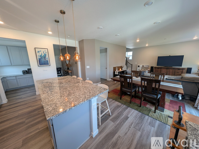 A modern kitchen with granite countertops and a dining area with a table and chairs.