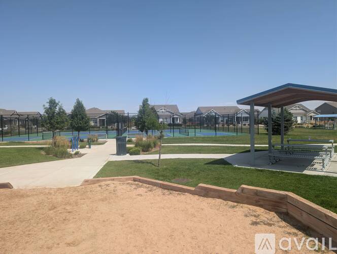 A sandy area in front of a pavilion with a pool in the background.