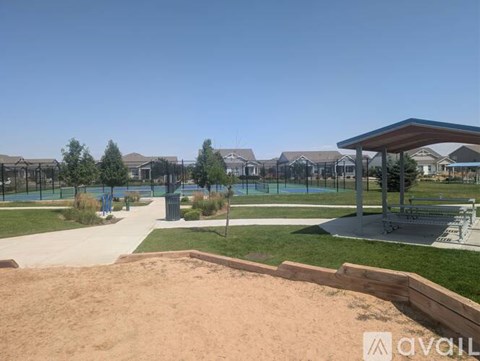 A sandy area in front of a pavilion with a pool in the background.