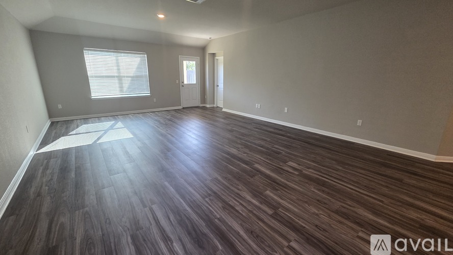 A spacious room with wooden flooring and a window.