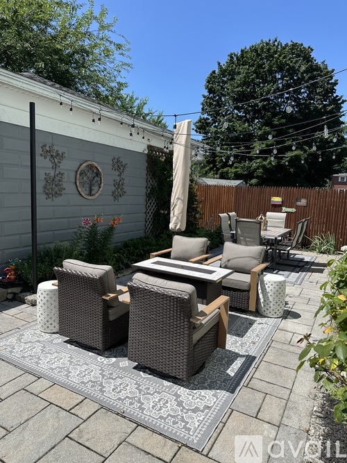 A patio with a grey couch and a white rug.