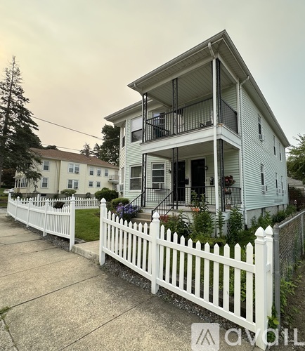 A white house with a balcony and a white picket fence.