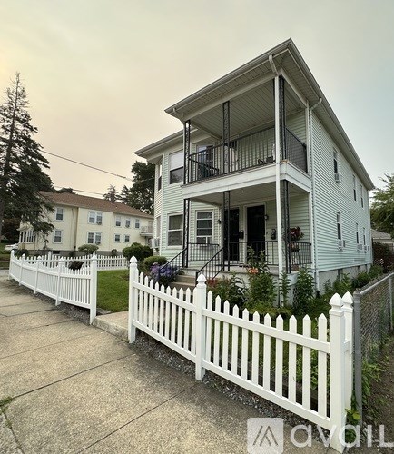 A white house with a balcony and a white picket fence.
