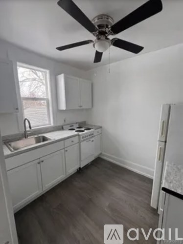 A kitchen with white cabinets and a fan.