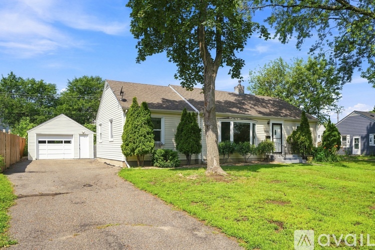 A house with a driveway and a tree in front.