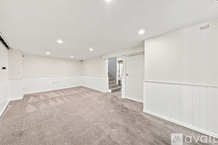 A spacious room with a carpeted floor and white walls.