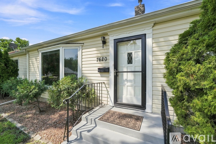 A house numbered 7620 with a black door and a black metal railing.