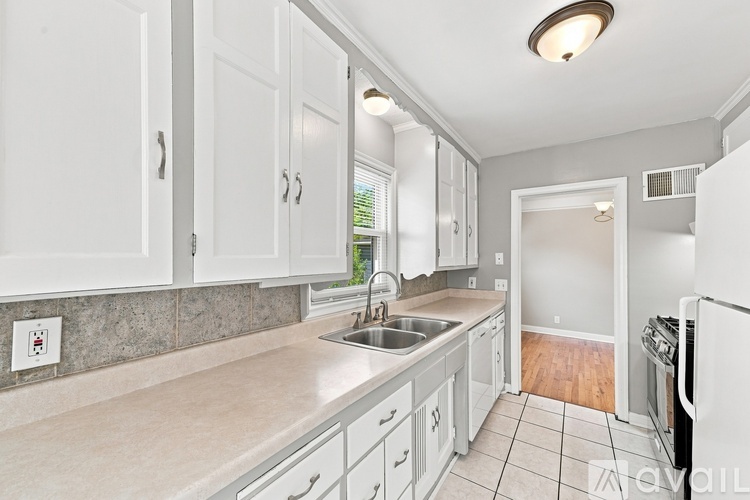 A kitchen with white cabinets and a tiled floor.
