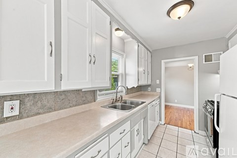 A kitchen with white cabinets and a tiled floor.