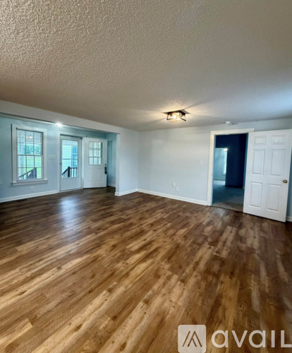 A room with wooden flooring and white walls.
