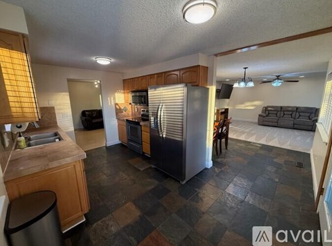 A kitchen with a checkered floor and a refrigerator in the middle.