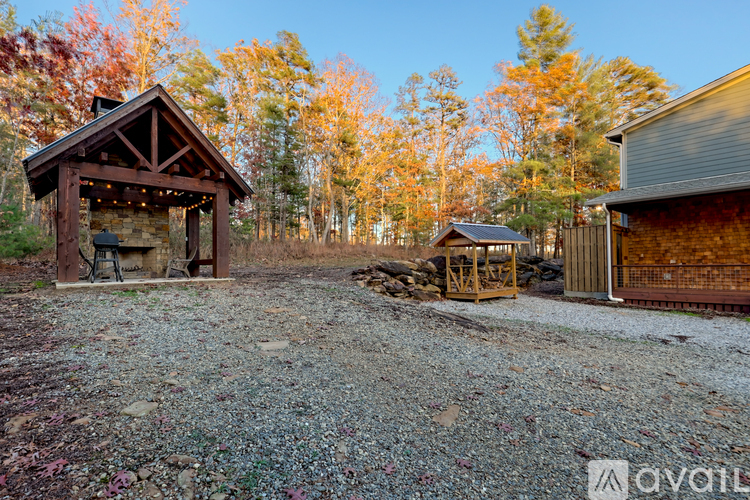 A gravel area with a wooden gazebo and a shed.