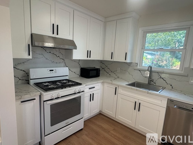 A kitchen with white cabinets and a marble countertop.