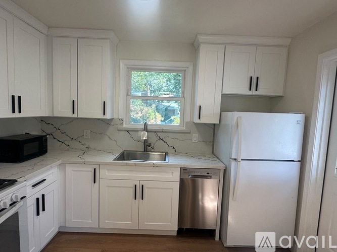 A kitchen with white cabinets and a marble countertop.