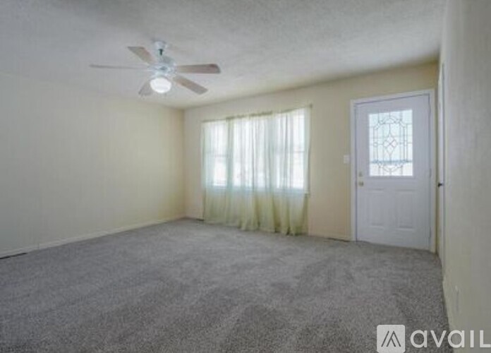 A room with a ceiling fan and a door with a glass window.