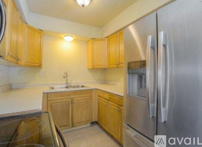 A kitchen with wooden cabinets and a stainless steel refrigerator.